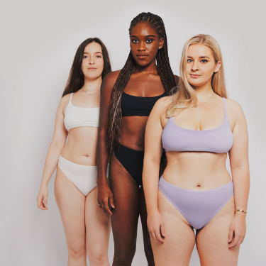 Three feminine presenting people of different ethnicities are modelling Magi’s bralettes with matching bottoms
